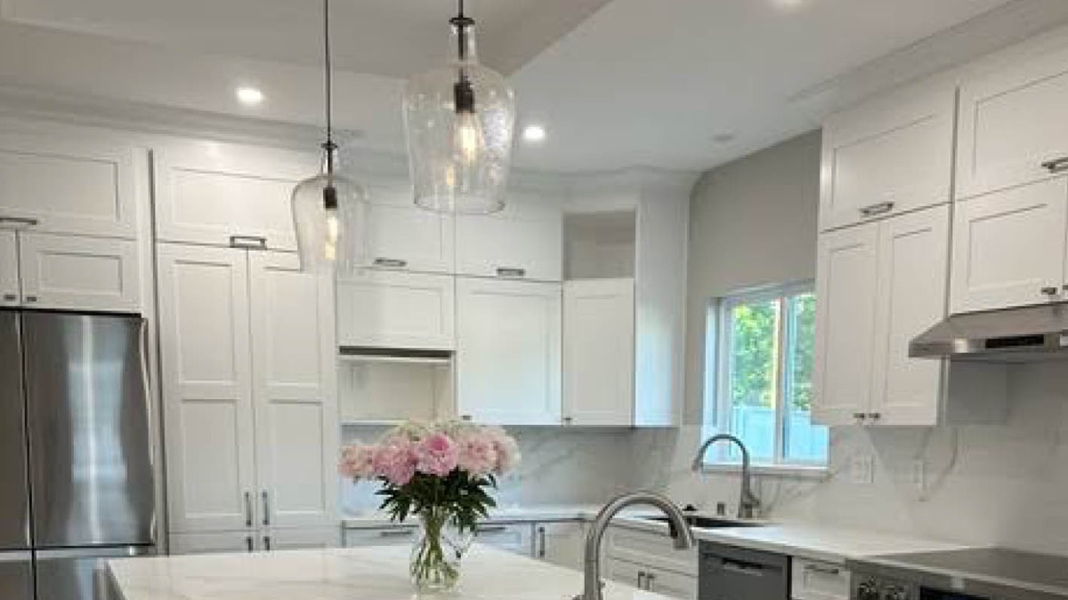 A remodelled kitchen with glass pendant lights over a quartz island and recessed ceiling lighting throughout.