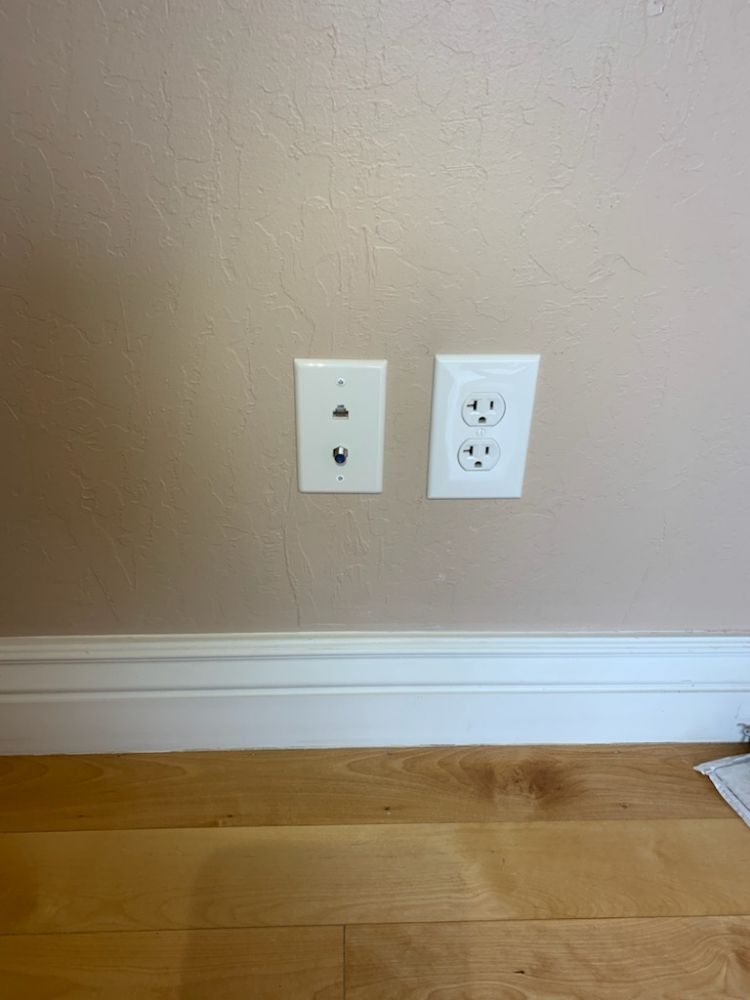 Finished data outlet and 20-amp receptacle trimmed out flush and square above the baseboard.