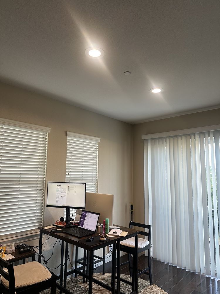 Recessed ceiling lights installed on an even grid, throwing clean overlapping pools of light down a wall.